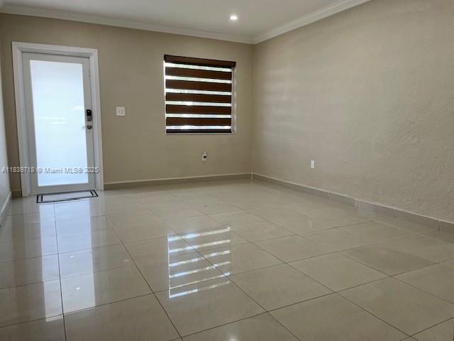 An empty room features light-colored tile flooring, beige walls, and a door with frosted glass — 330 W 40th Pl, Hialeah FL 33012, HIALEAH, FL