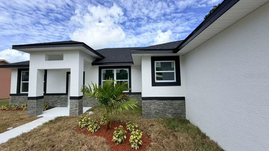 A modern single-story house exterior features white stucco walls, stone veneer accents, and dark trim — 1217 E PRICE BOULEVARD, NORTH PORT, FL