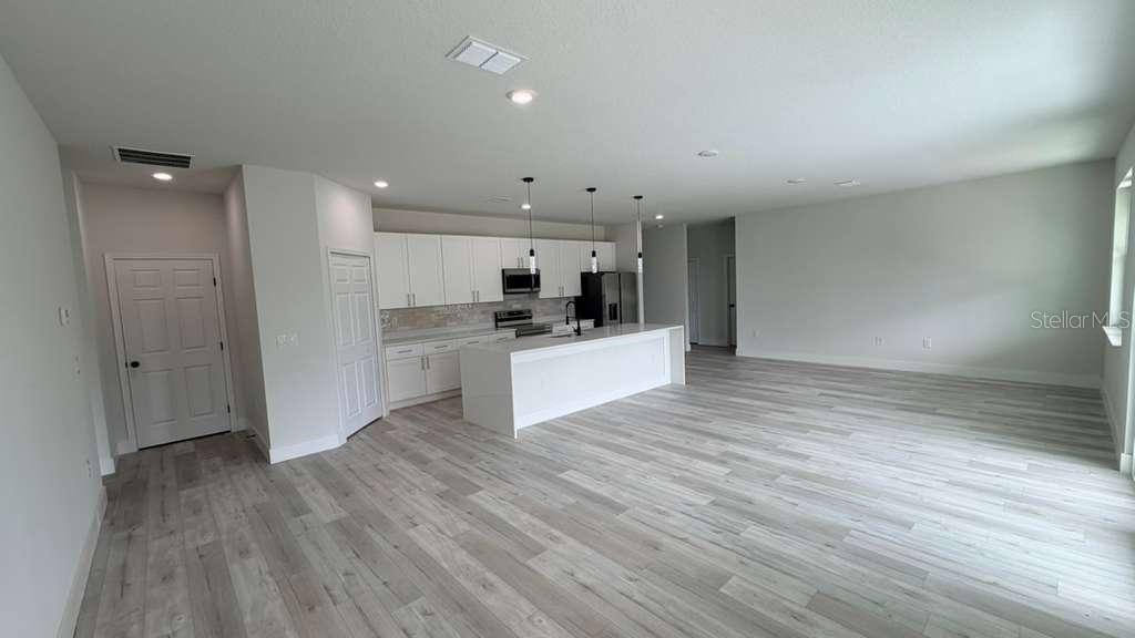 A modern open-concept kitchen features white cabinetry, a large island, and light wood-look flooring — 1217 E PRICE BOULEVARD, NORTH PORT, FL