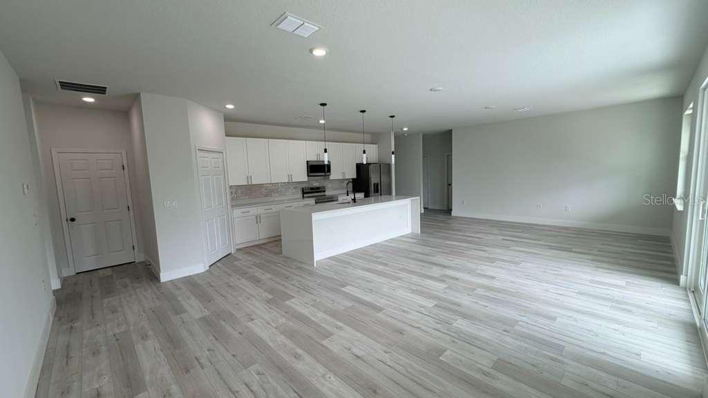 A modern open-concept kitchen features white cabinetry, a central island, and light wood-look flooring — 1217 E PRICE BOULEVARD, NORTH PORT, FL