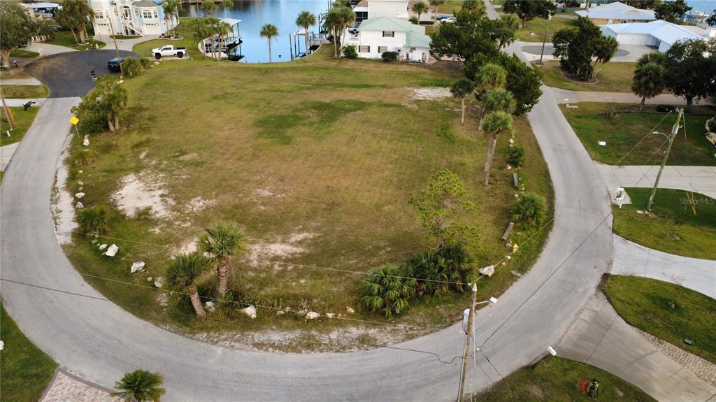 An aerial view shows a vacant, grassy corner lot surrounded by a curved residential road — 11999 W BAYSHORE DRIVE, CRYSTAL RIVER, FL