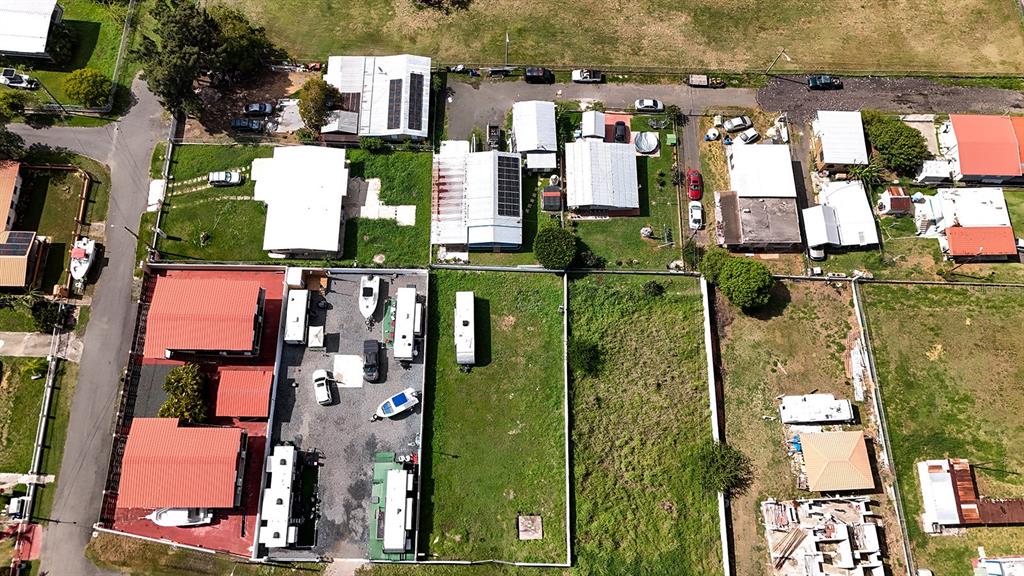 Aerial view of a residential neighborhood featuring houses, a gravel lot with trailers, and vacant land — CARR 3301 W COMBATE, CABO ROJO, PR