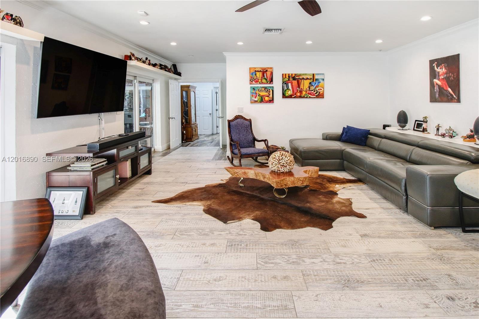 A living room features a large sectional sofa, a cowhide rug, and wood-look tile flooring — 19901 NE 21st Ave, Miami FL 33179, MIAMI, FL
