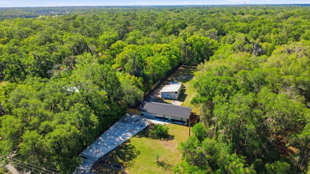 An aerial view shows a house with a dark roof and a detached shed nearby — 550 E MINNESOTA AVENUE, ORANGE CITY, FL