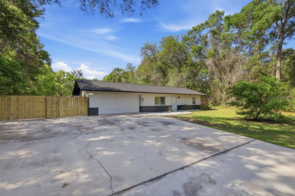 A single-story house with a white exterior, dark roof, and a large concrete driveway — 550 E MINNESOTA AVENUE, ORANGE CITY, FL