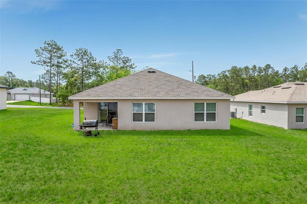 The rear exterior of a single-story house features a small covered patio and lawn — 14944 SW 66TH AVENUE ROAD, OCALA, FL