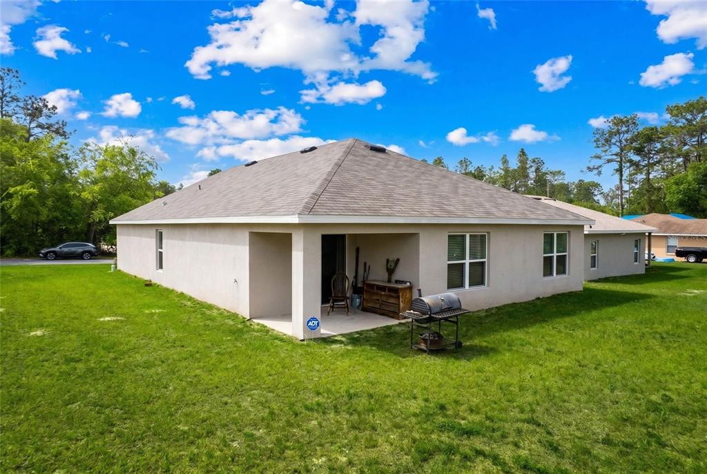 The exterior rear view of a single-story house features a covered patio and lawn — 14944 SW 66TH AVENUE ROAD, OCALA, FL