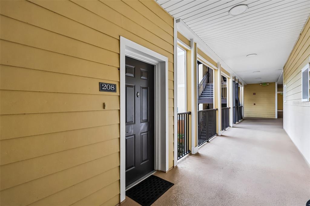 An exterior hallway features a dark brown apartment door numbered 208 and black railings — 9055 TREASURE TROVE LANE UNIT 208, KISSIMMEE, FL