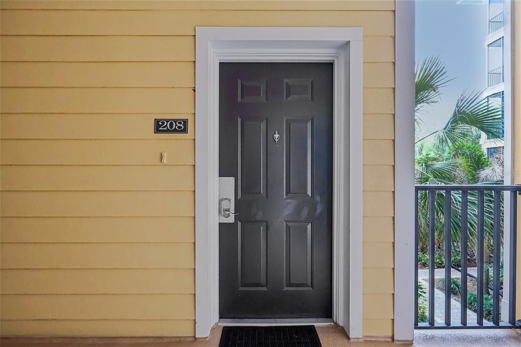 A dark gray front door with a number 208 sign on yellow siding — 9055 TREASURE TROVE LANE UNIT 208, KISSIMMEE, FL