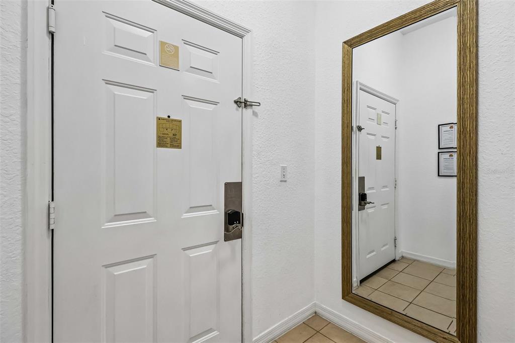 A white interior door with a security lock and a large wall-mounted mirror — 9055 TREASURE TROVE LANE UNIT 208, KISSIMMEE, FL