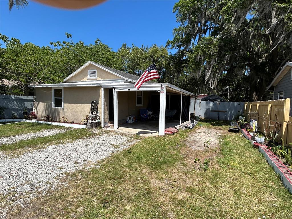 A single-story house with a gravel driveway, a covered porch, and an American flag — 629 HOLMES AVENUE, DAYTONA BEACH, FL