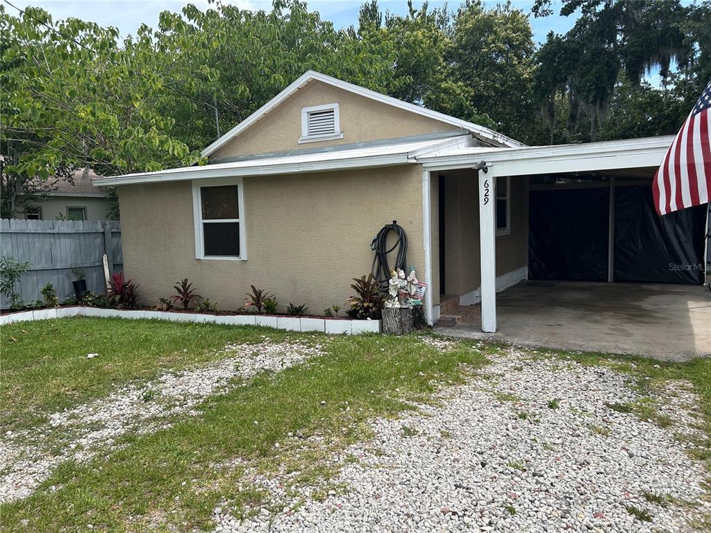A tan, single-story house with a gravel driveway and an attached carport — 629 HOLMES AVENUE, DAYTONA BEACH, FL