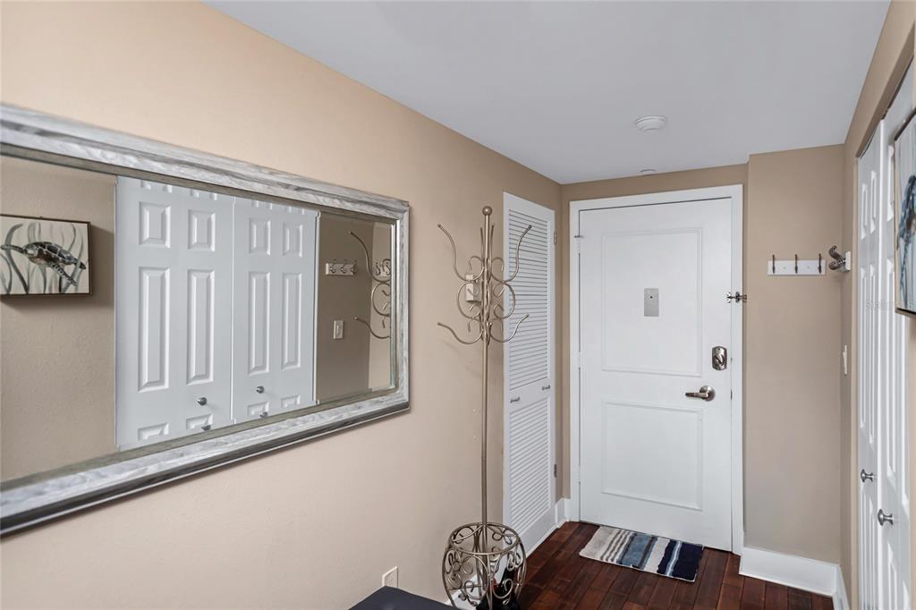 An entryway features a large wall mirror, a coat rack, and a white front door — 1212 BENJAMIN FRANKLIN DRIVE UNIT 303, SARASOTA, FL