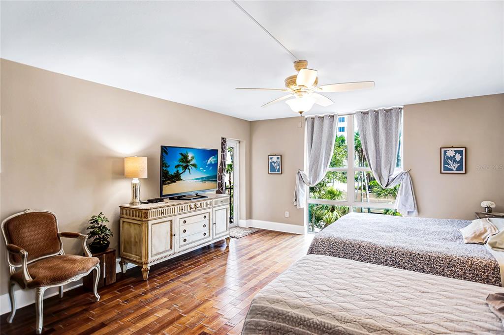 A bedroom with wood-look flooring, two beds, a ceiling fan, and a television on a dresser — 1212 BENJAMIN FRANKLIN DRIVE UNIT 303, SARASOTA, FL