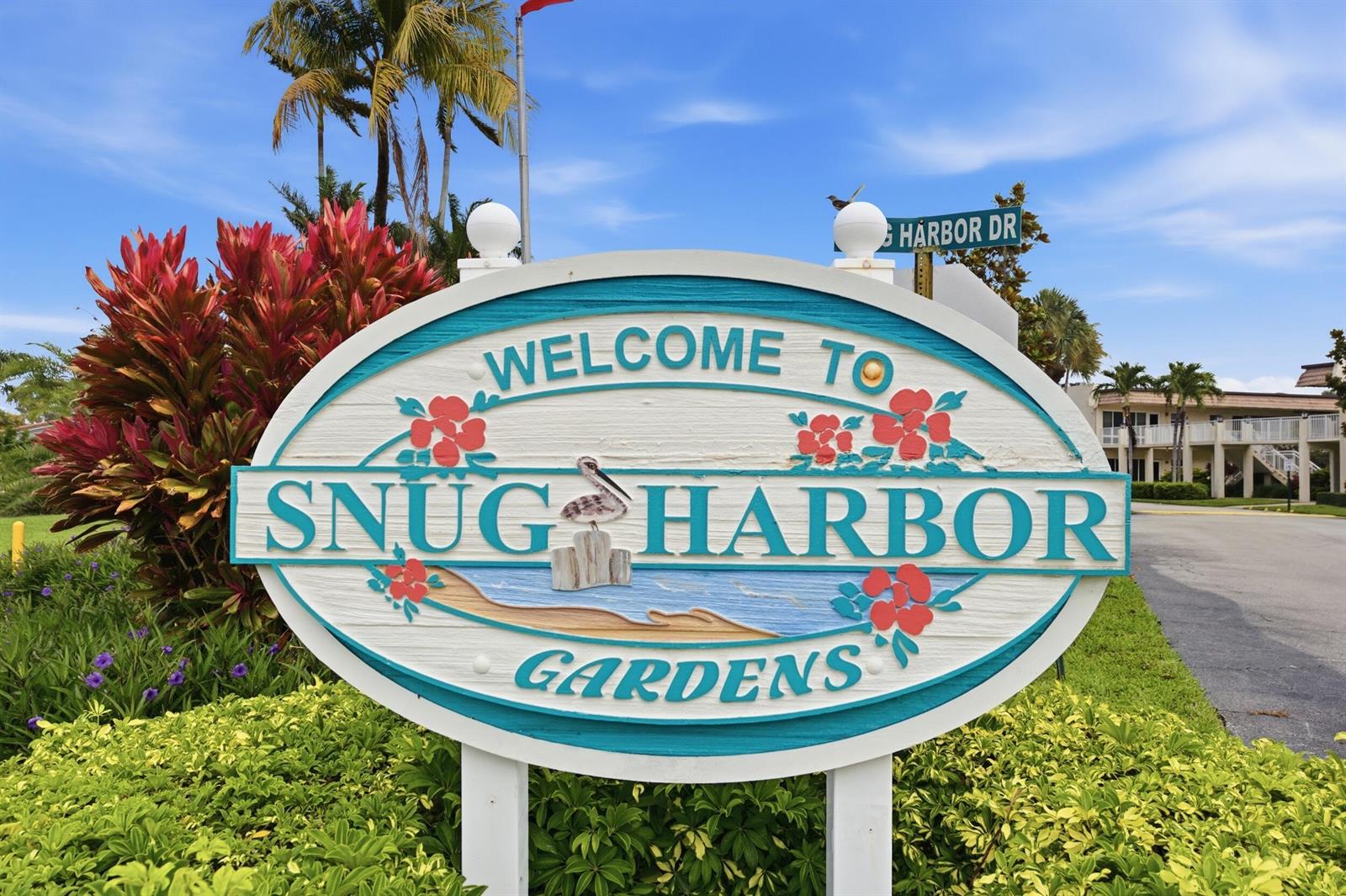 An oval sign welcomes visitors to Snug Harbor Gardens near a street sign and palm trees — 600 Snug Harbor Drive # A10, Boynton Beach FL 33435, BOYNTON BEACH, FL