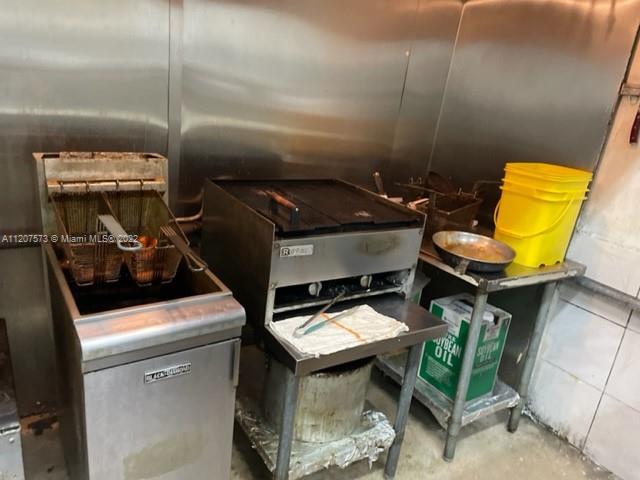 A commercial kitchen features a stainless steel deep fryer, a flat-top grill, and a yellow bucket — 8726 NW 26th St, Doral FL 33172, DORAL, FL