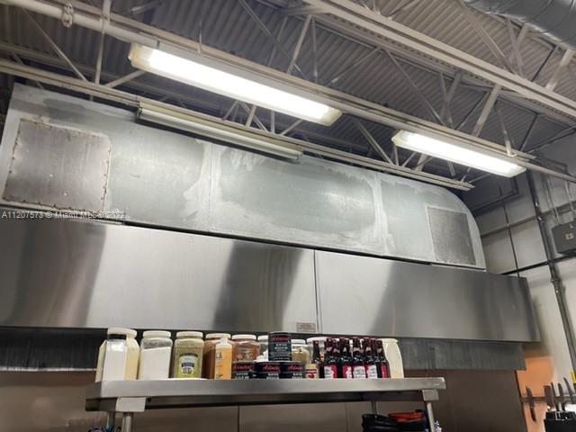 A stainless steel commercial kitchen hood hangs above a shelf containing various food containers — 8726 NW 26th St, Doral FL 33172, DORAL, FL