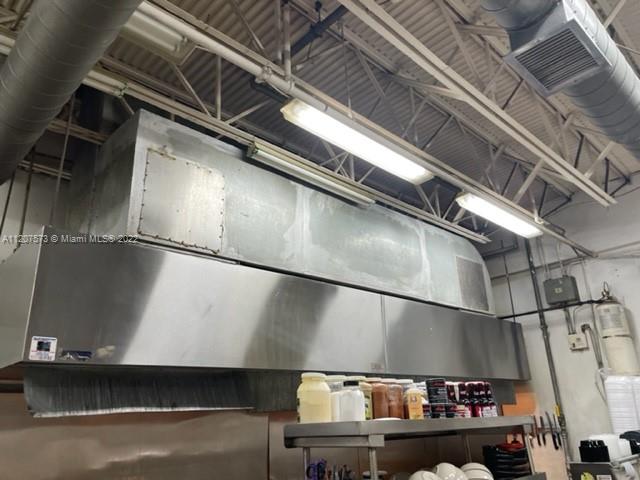 A stainless steel commercial kitchen exhaust hood is mounted above a metal prep table — 8726 NW 26th St, Doral FL 33172, DORAL, FL