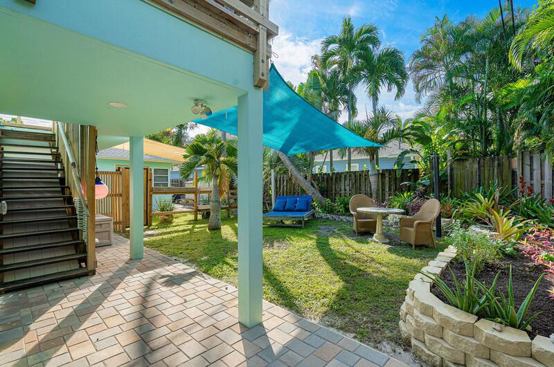 A backyard features a paved patio, a grassy lawn, a blue shade sail, and seating — 300 SE 7th Avenue, Delray Beach FL 33483, DELRAY BEACH, FL