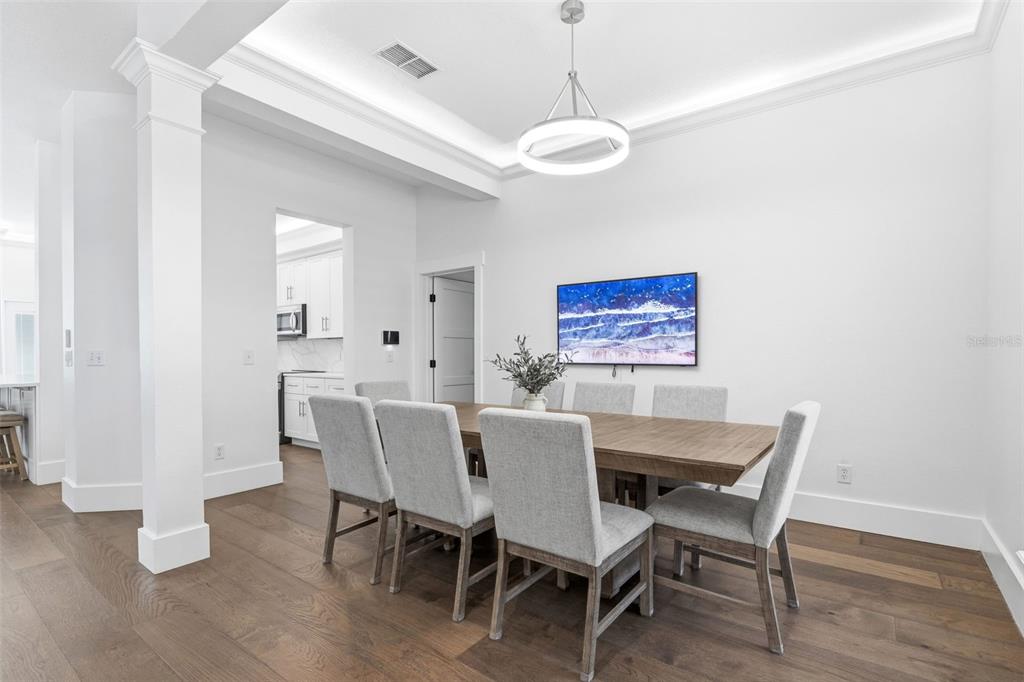 A living room features a white sectional sofa, a staircase, and large windows with blinds — 185 LONGVIEW AVENUE, KISSIMMEE, FL