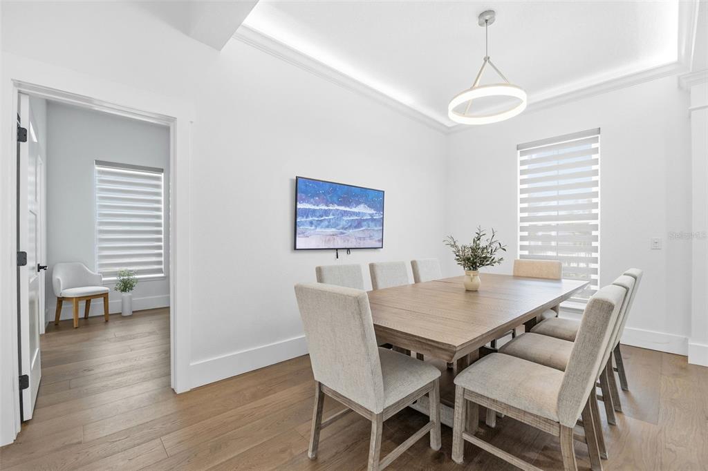 A dining room features a wooden table, six gray chairs, and a modern pendant light — 185 LONGVIEW AVENUE, KISSIMMEE, FL