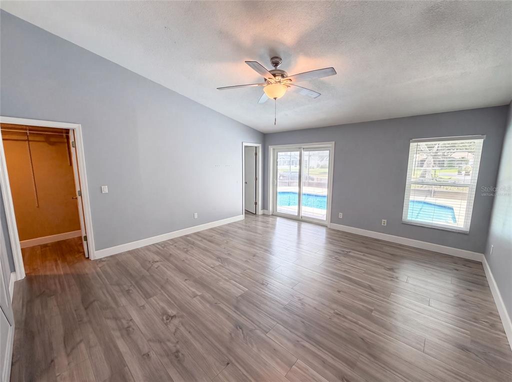 A bedroom with gray walls, wood-look flooring, a ceiling fan, and sliding glass doors to a pool — 3800 SEMINOLE DRIVE, ORLANDO, FL