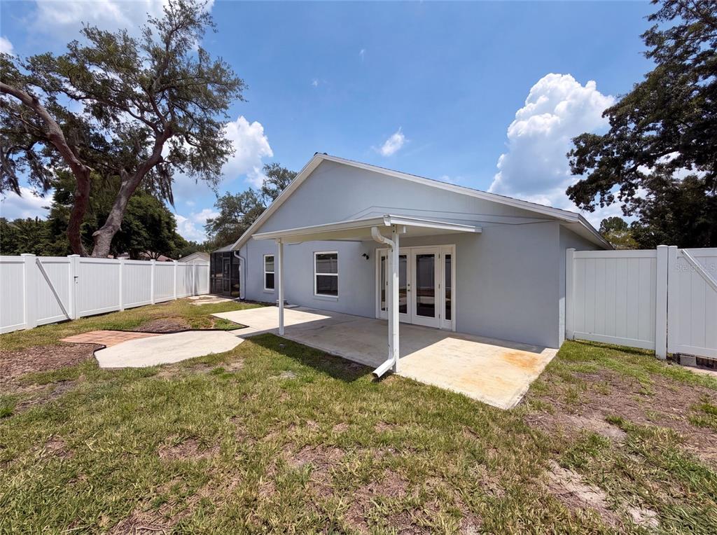 The exterior of a light-gray house features a covered concrete patio and white vinyl fencing — 3800 SEMINOLE DRIVE, ORLANDO, FL
