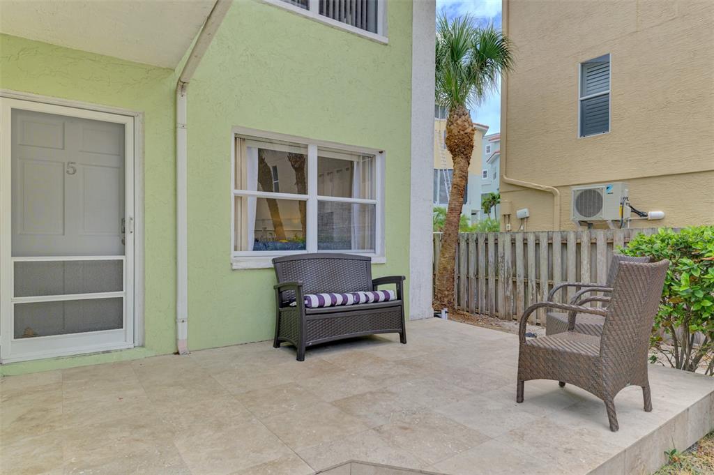 A patio with a light green exterior wall, a bench, and a chair — 446 CANAL ROAD UNIT 5, SARASOTA, FL