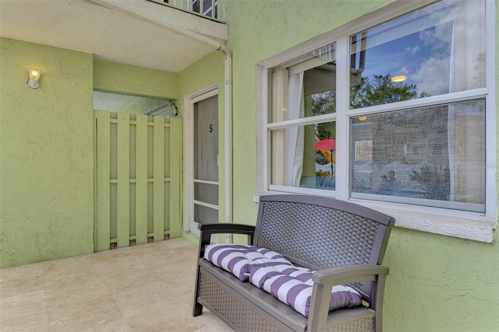 A light green exterior wall features a patio bench, a screen door, and a window — 446 CANAL ROAD UNIT 5, SARASOTA, FL