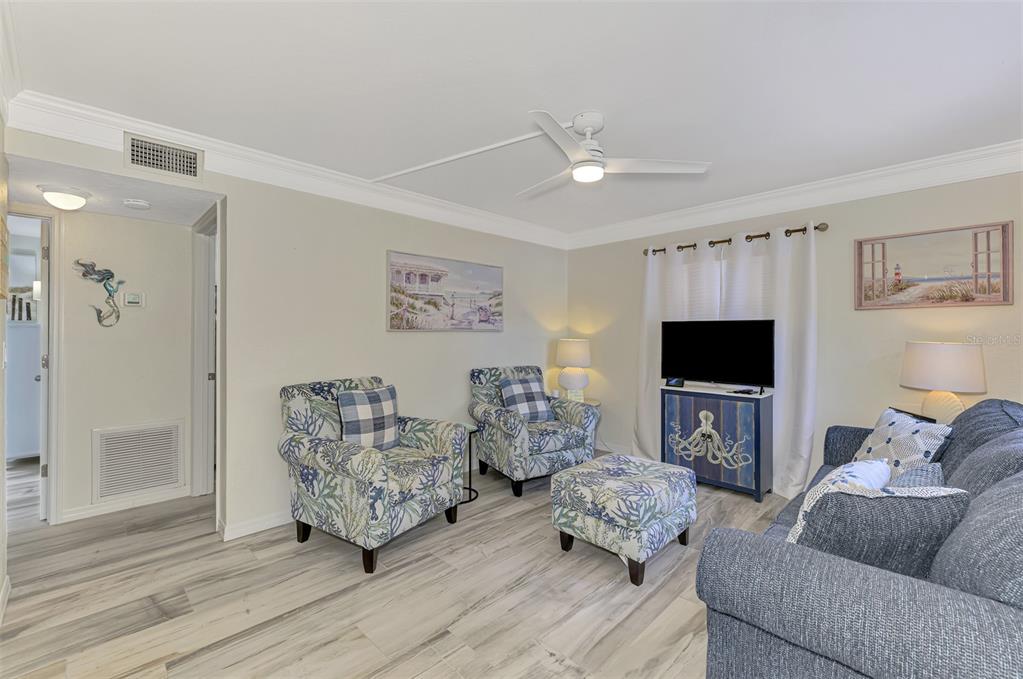 A living room features light wood-look flooring, two patterned armchairs, a matching ottoman, and sofa — 446 CANAL ROAD UNIT 5, SARASOTA, FL