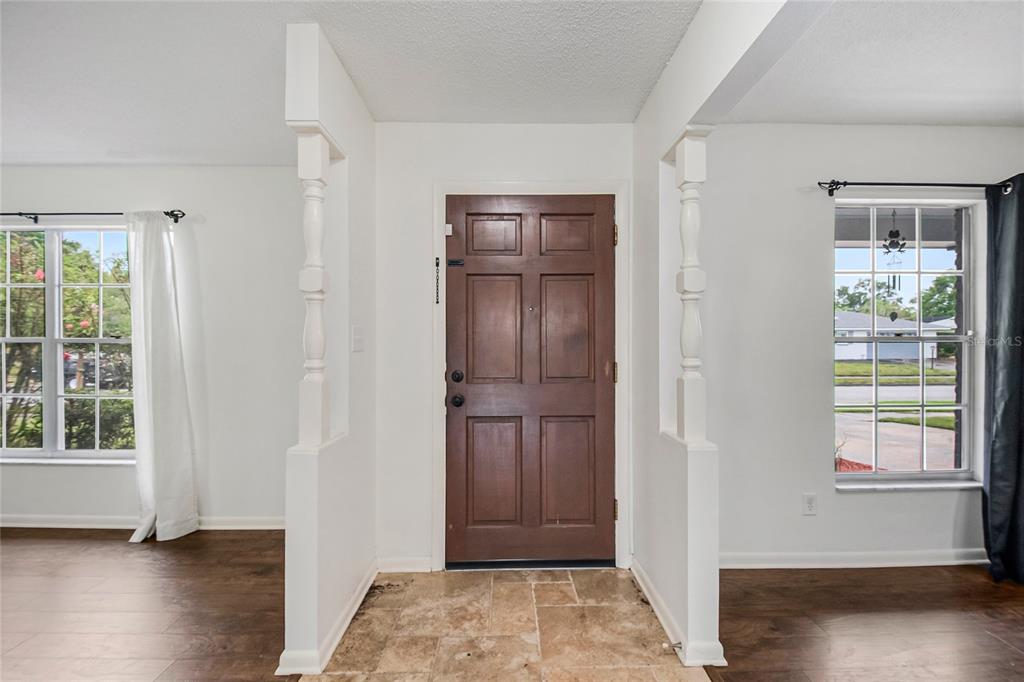 An entryway features a brown front door, tiled floor, and white columns separating adjacent rooms — 4931 TELLSON PLACE, ORLANDO, FL
