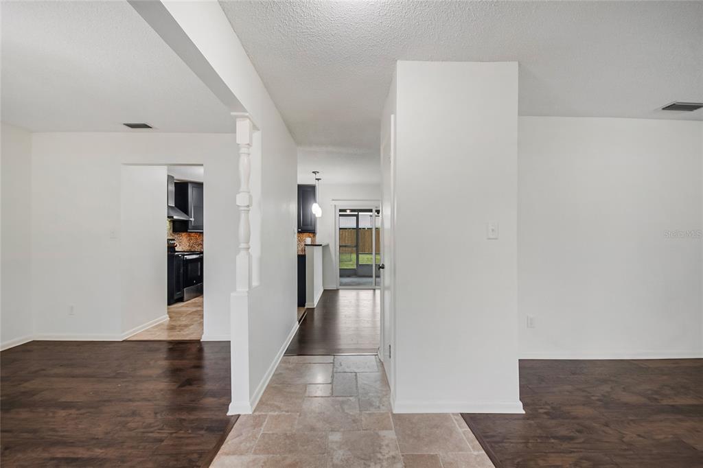 A view through a hallway with tile flooring connecting a kitchen and a living area — 4931 TELLSON PLACE, ORLANDO, FL