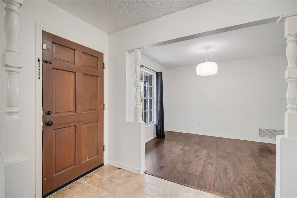 An entryway with a wooden door and tile floor opens into a dining room area — 4931 TELLSON PLACE, ORLANDO, FL