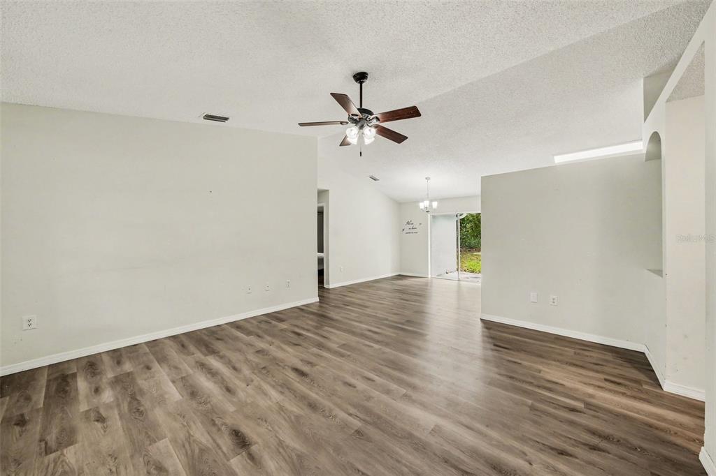 An empty living room with wood-look flooring, a ceiling fan, and sliding glass doors — 1166 15TH STREET, ORANGE CITY, FL