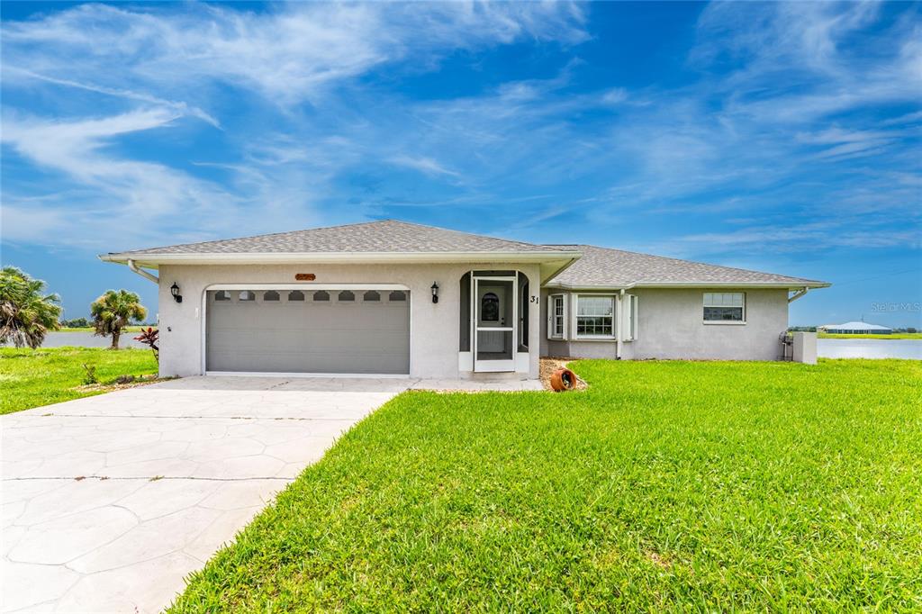 A single-story house with a gray garage, a front door, and a grassy lawn — 31 MEADOWLARK LANE, PLACIDA, FL