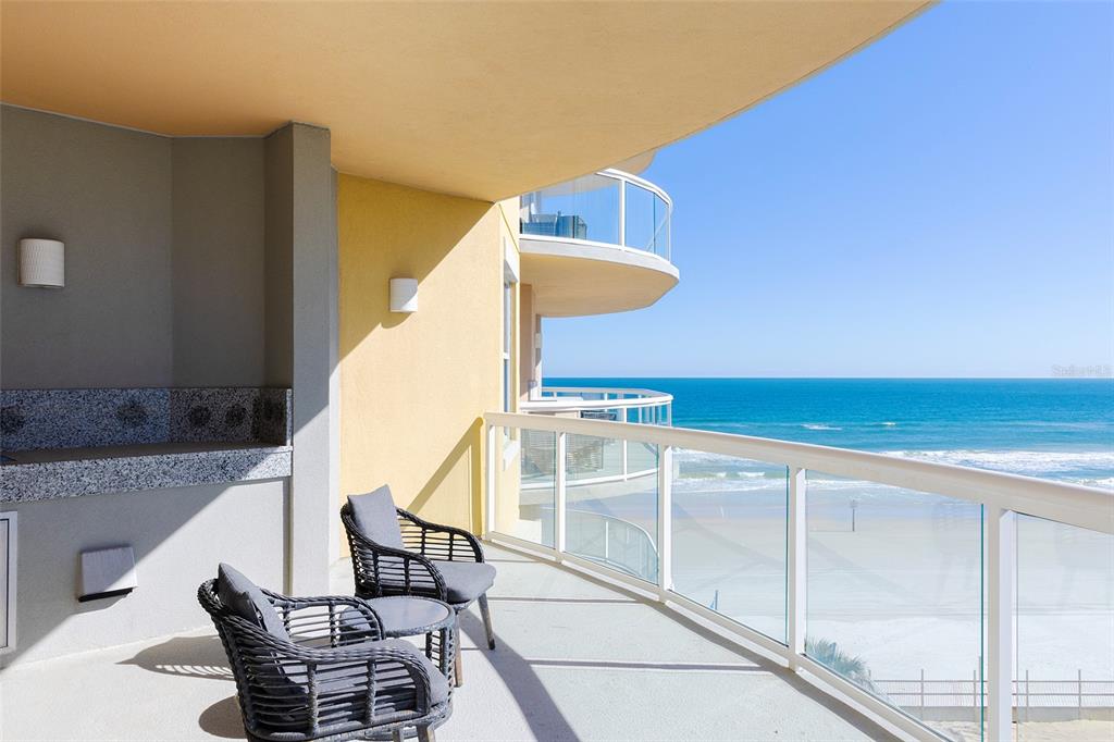 A balcony with outdoor seating overlooks the ocean and a sandy beach — 3703 S ATLANTIC AVENUE UNIT 505, DAYTONA BEACH SHORES, FL