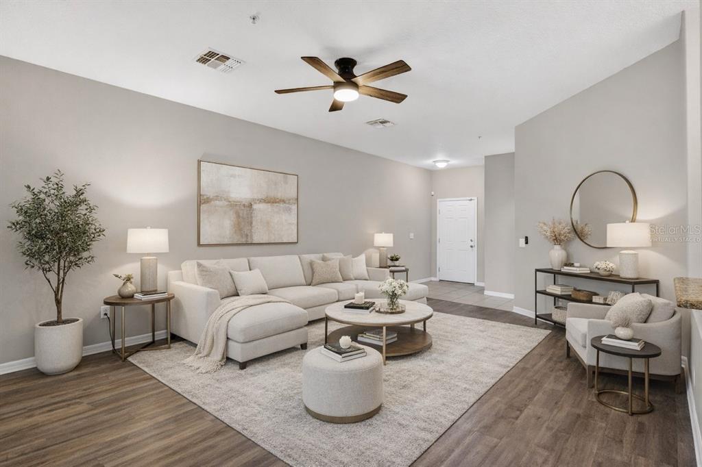 A living room features a sectional sofa, round coffee table, and wood-look flooring — 1519 PRIORY CIRCLE, WINTER GARDEN, FL