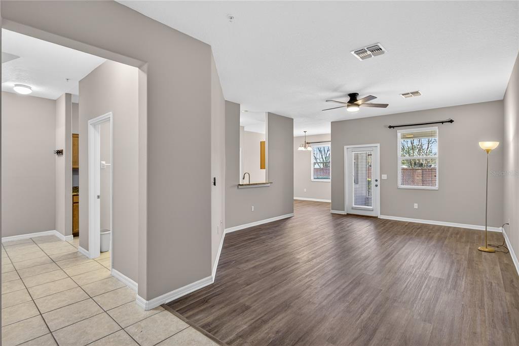 An open-concept living area features wood-look flooring, neutral walls, a ceiling fan, and a doorway — 1519 PRIORY CIRCLE, WINTER GARDEN, FL