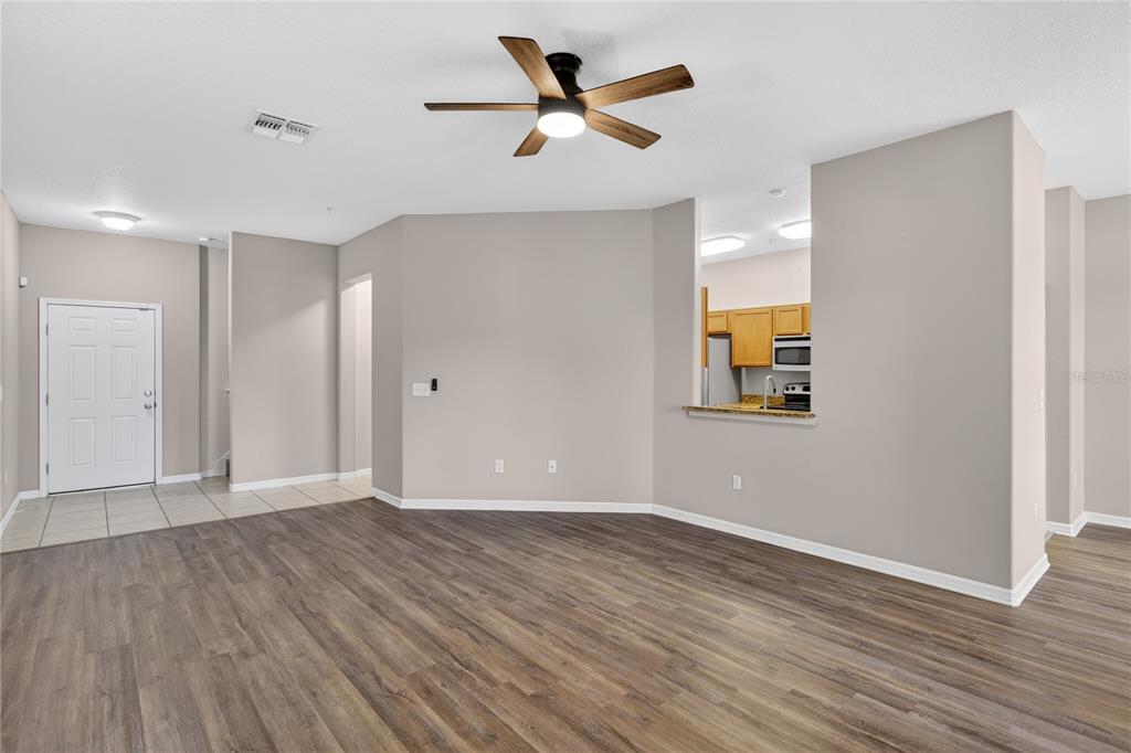 An open-concept living area features wood-look flooring, a ceiling fan, and a kitchen pass-through window — 1519 PRIORY CIRCLE, WINTER GARDEN, FL