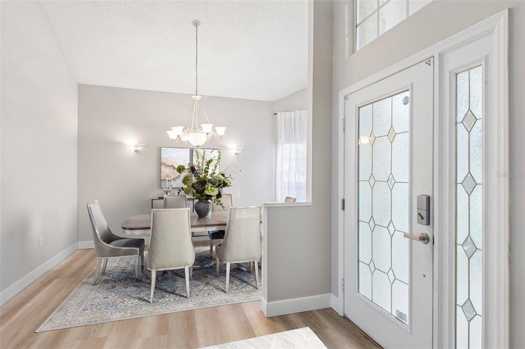 A dining room with a chandelier and rug sits adjacent to a white front door — 586 KINGSMILL COURT, OLDSMAR, FL