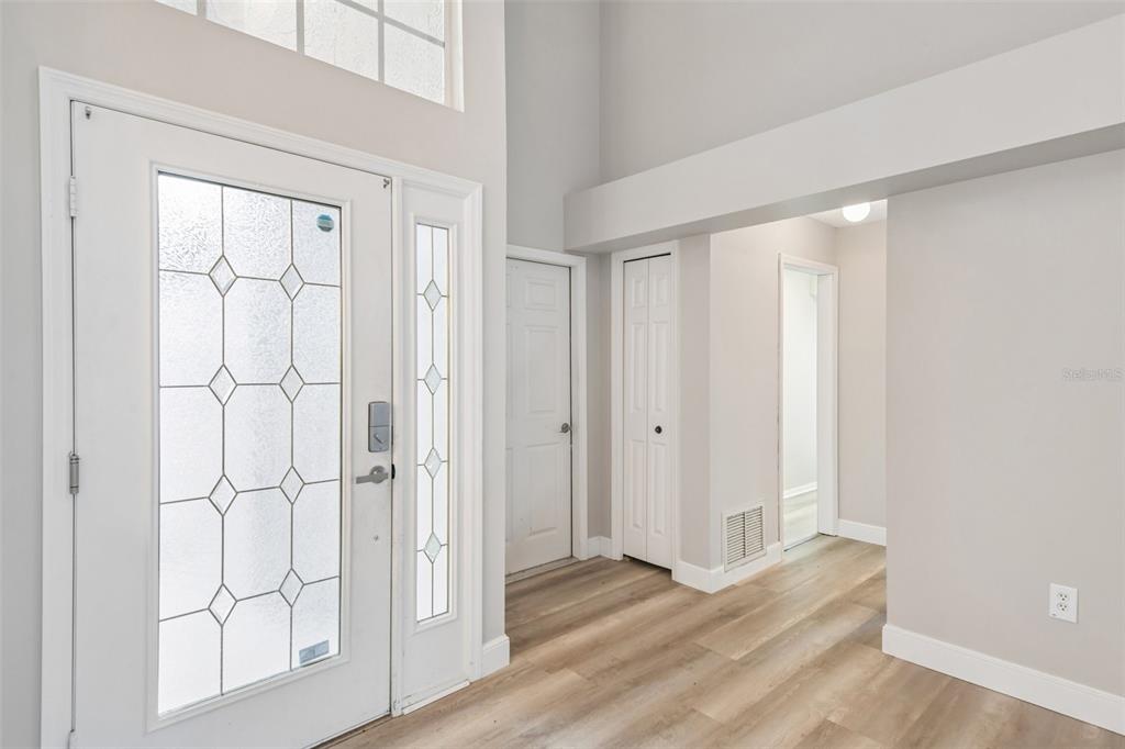 An entryway features a white front door with glass panels, light wood flooring, and closets — 586 KINGSMILL COURT, OLDSMAR, FL
