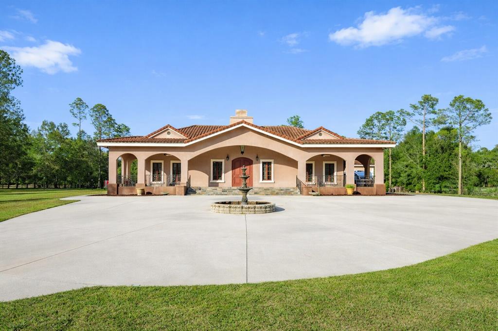 A single-story stucco house with a tile roof and a front fountain in a yard — 18910 NW 78TH AVENUE, ALACHUA, FL