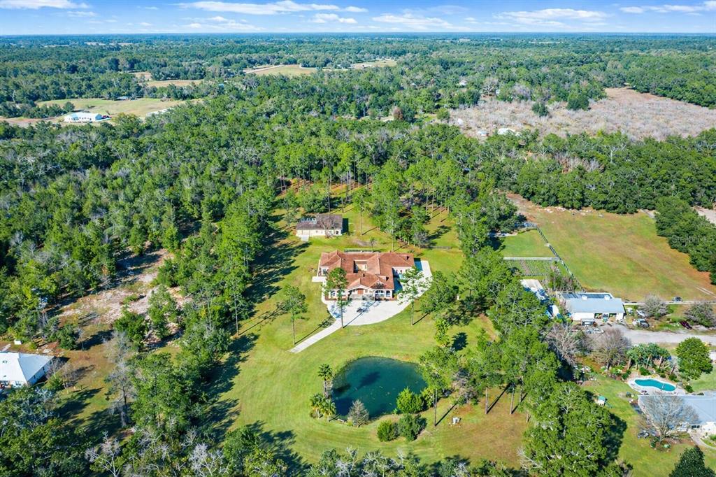 An aerial view shows a large house with a pond, surrounding trees, and open land — 18910 NW 78TH AVENUE, ALACHUA, FL