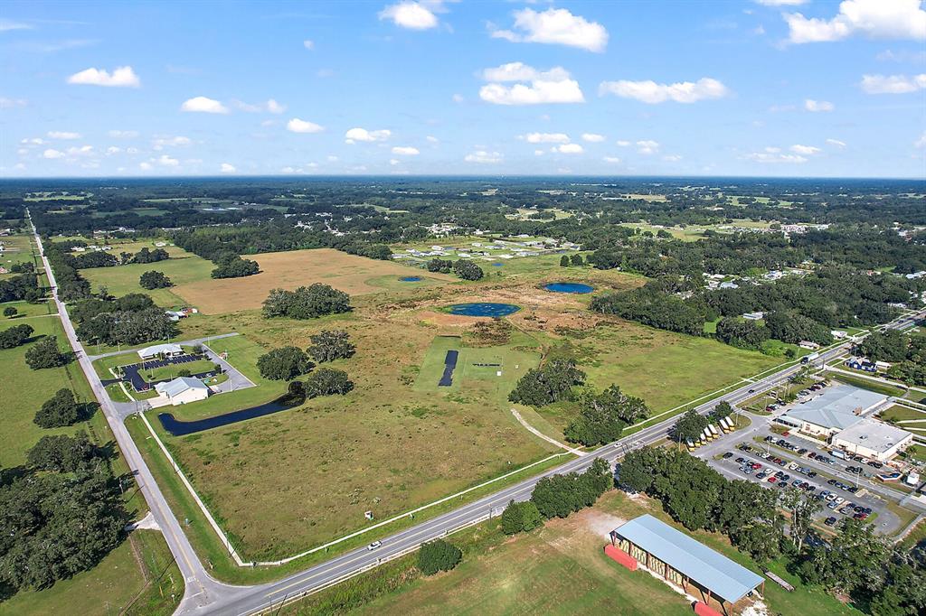 An aerial view shows a large, grassy undeveloped lot bordered by roads and commercial buildings — 416 S MARKET BOULEVARD, WEBSTER, FL