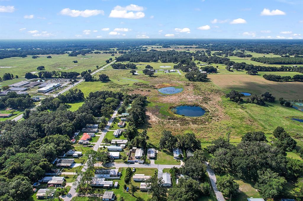 An aerial view shows a rural neighborhood with small houses, scattered trees, and two ponds — 416 S MARKET BOULEVARD, WEBSTER, FL