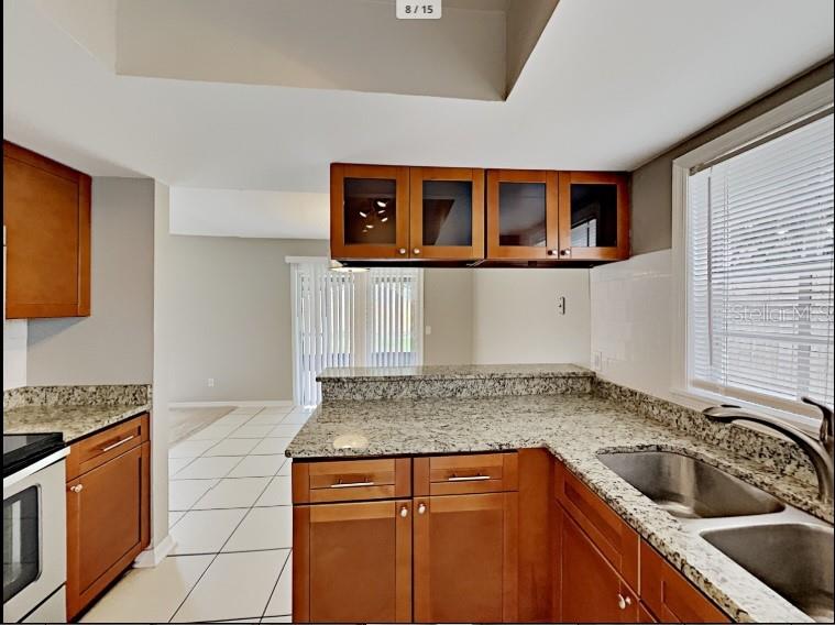 A kitchen features wood cabinets, granite countertops, a double sink, and tile flooring — 1680 PALM LEAF DRIVE, BRANDON, FL
