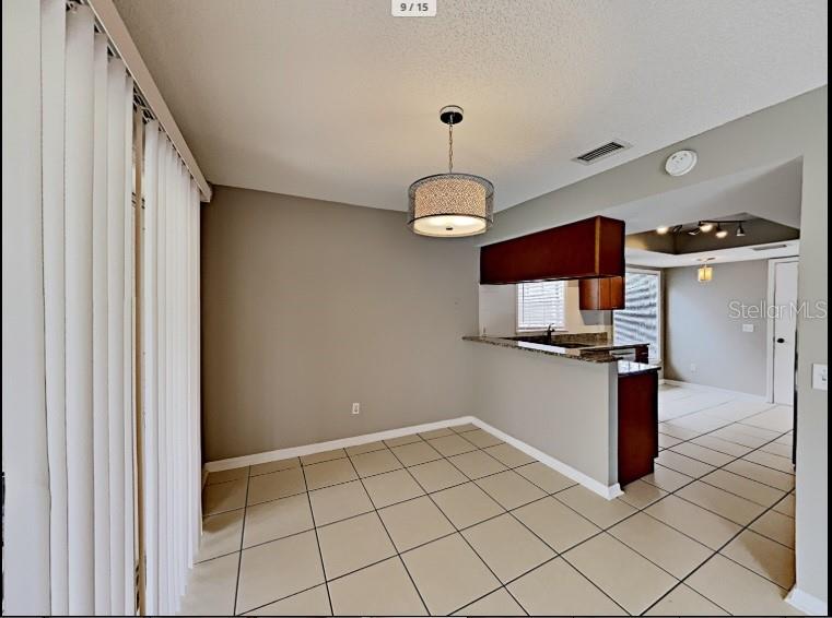 A dining area with tile flooring, a pendant light, and a pass-through kitchen counter — 1680 PALM LEAF DRIVE, BRANDON, FL