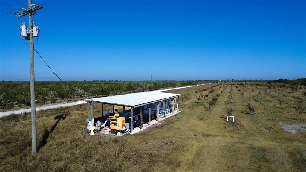 An aerial view shows a covered structure housing a mobile home in a rural field — NE HWY 70, ARCADIA, FL
