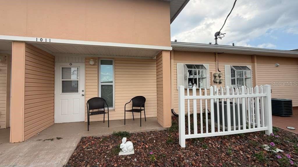 A peach-colored exterior features a covered entryway, a white door, and a white picket fence — 1011 CLUB CIRCLE, LAKE WALES, FL
