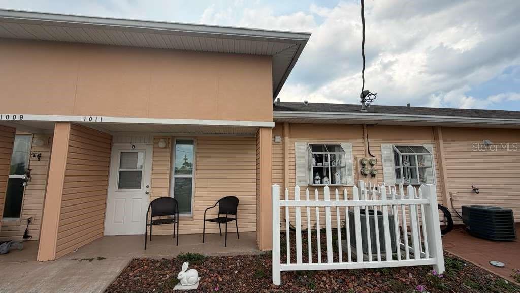 The exterior of a peach-colored duplex features a white picket fence and two chairs — 1011 CLUB CIRCLE, LAKE WALES, FL